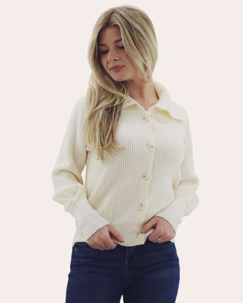 Front view of a woman wearing a cream collared ribbed button-down sweater, paired with dark denim jeans for a chic and cozy fall look.