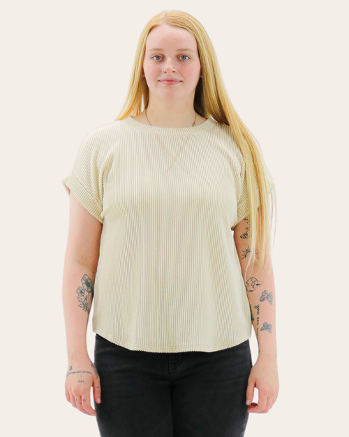 Front view of a textured short-sleeve knit top in a light hue with a crew neckline and rolled sleeves, styled with black jeans.