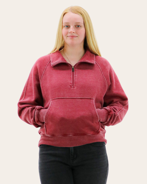 Front view of a woman in a red quarter-zip sweatshirt featuring a high collar, front pocket, and casual silhouette.