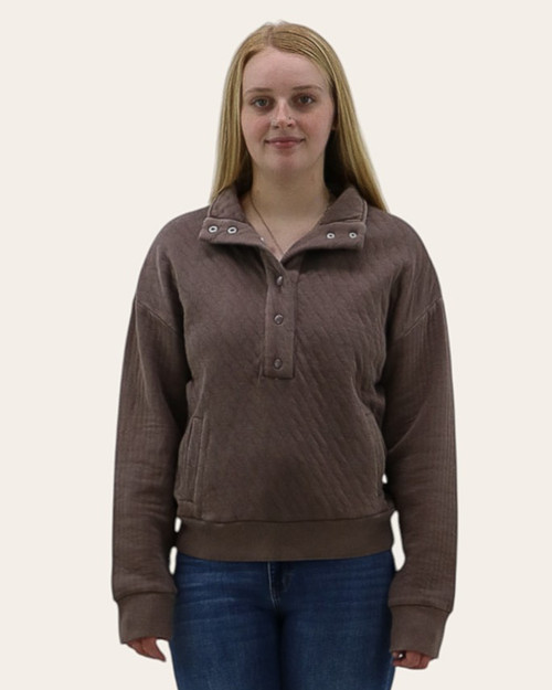 Front view of woman wearing a brown quilted pullover with snap-button collar open, showcasing casual fall style.