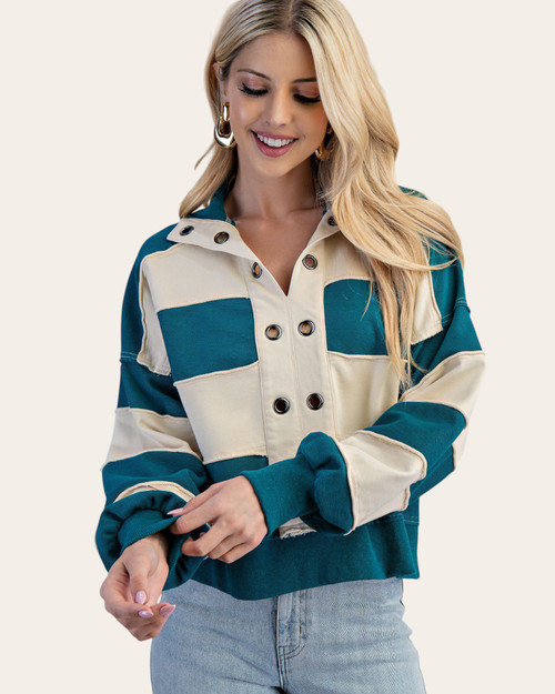 Front view of model wearing a striped pullover with oversized grommet details and cuffed sleeves.