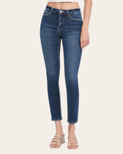 Woman wearing high-rise skinny jeans in medium blue wash, front view with cropped top and strappy sandals.