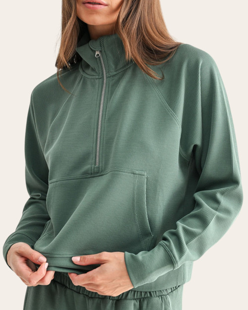 Close up front view of a model wearing the Eldergreen Luxe Ribbed 1/2 Zip Sweatshirt featuring a kangaroo pocket and silver zipper.