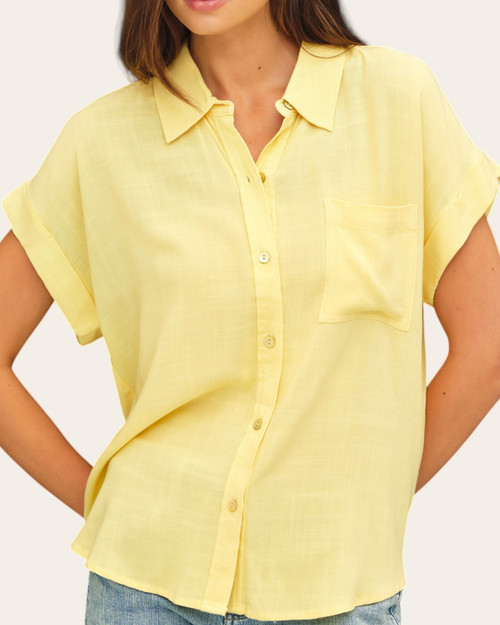 Close up of a bright yellow button down short sleeve top featuring a chest pocket from our South Dakota boutique.