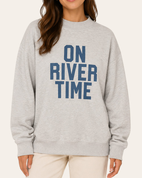 Front view of the On River Time Mock Neck Sweatshirt in heather grey with blue block lettering, styled on a model.