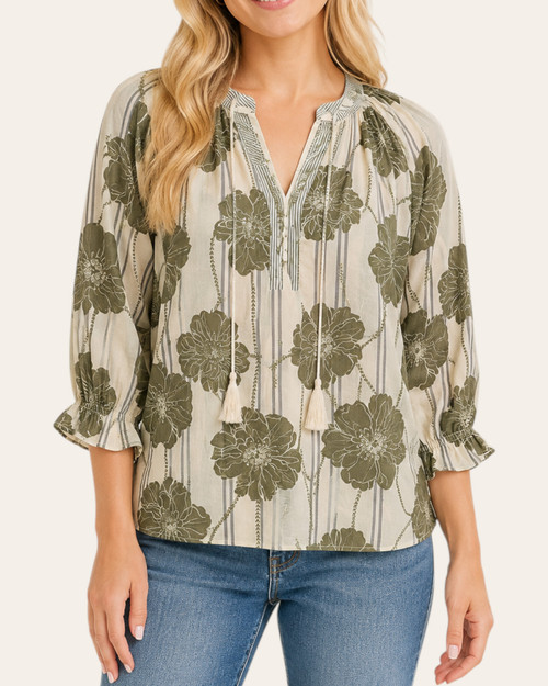 Woman wearing a sage green botanical print pintuck blouse with a v-neck and striped collar, front view.