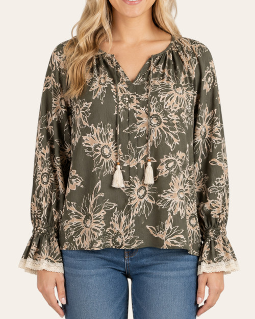 Woman modeling the front of the Freya Floral Print Blouse in olive green with abstract floral design and tassel neckline.