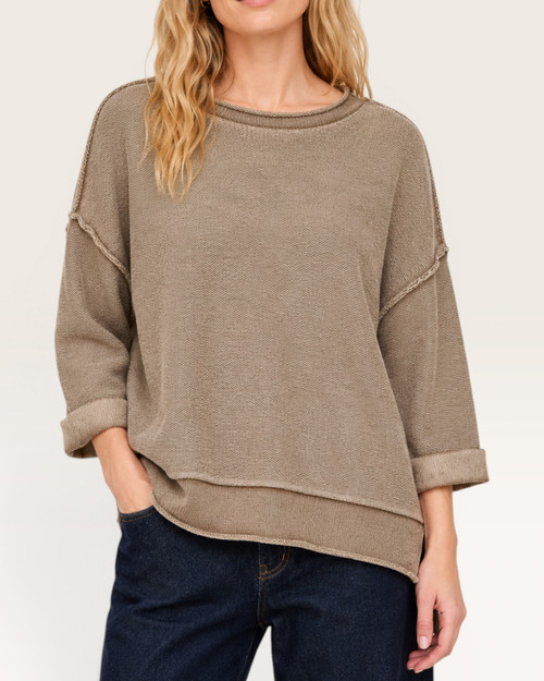 Woman modeling a comfortable, oversized mocha short sleeve sweatshirt paired with dark denim.