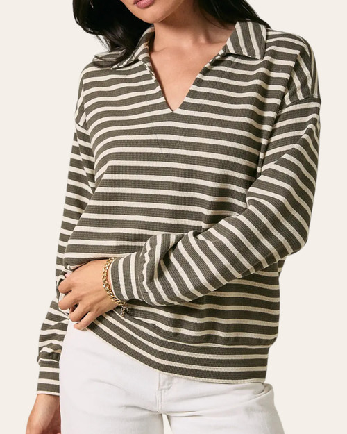 Woman wearing the fall-ready Finley lightweight striped knit top in olive and cream with a v-neck collar, front half-body view.