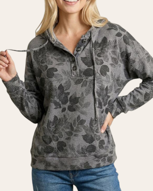Woman modeling the front of the dark charcoal Peace Gardens Leafy Print Hooded Top with neckline button details.