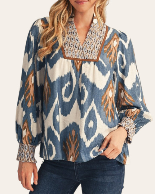 Front styling of a long-sleeve teal abstract print blouse with elastic smocked cuffs, paired with dark denim for a Midwest autumn look.