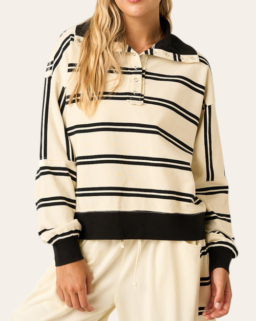Front view of the Kingston Snap Collar Sweatshirt worn by a blonde model, showing the striking cream and black striped pattern, open snap neckline, and comfortable ribbed black hem.