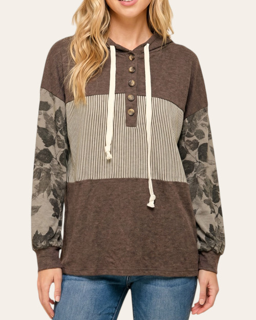 Front view of a model wearing the Peace Gardens top, showcasing the button-up neckline, cream striped center panel, and drawstrings against a solid brown chest.