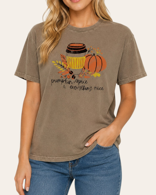 Blonde woman modeling a short-sleeve washed light mocha t-shirt with a pumpkin and coffee graphic reading pumpkin spice and everything nice, paired with blue denim.