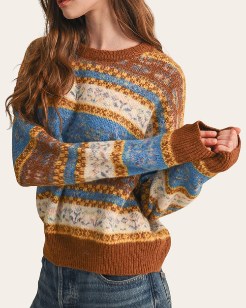 Maggie Printed Sweater - Toffee/Ocean modeled with arms bent, showing blue, brown and cream patterned bands and toffee ribbed cuffs.