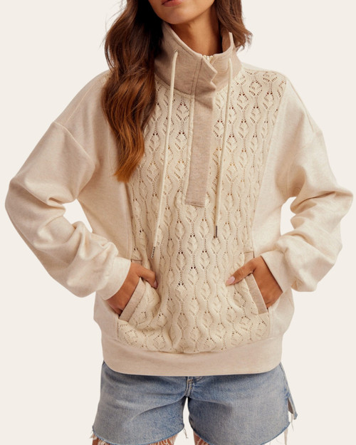 Crochet Detail Quarter Zip Pullover - Oatmeal on a model, with hands in the front pocket openings and a raised drawcord collar.