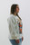 Side profile of a Trendy Threads Boutique model posing in a casual cream sweatshirt with a vibrant Grand Canyon graphic, complemented by fitted light-wash jeans, ideal for a relaxed spring day.