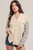 A woman models the Share Your Thoughts Shacket, a new arrival that transitions seamlessly through the seasons. The piece features a cream-colored bodice with contrasting navy color block side panels, and the sleeves showcase a playful stripe pattern. It's completed with a button front closure, raw hem, and dual chest pockets.