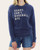 Front view of the navy blue Sorry Can't Baseball graphic sweatshirt featuring beige text, styled with denim shorts.