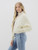 Side view of the model showcasing the Jayda Jacket with full zip closure, sweater sleeves, and cropped fit, styled with light wash jeans.
