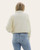 Back view of women’s ivory sweater jacket with knit sleeves and ribbed hem, paired with light wash jeans.