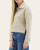 Side profile showing the cropped boxy silhouette and side slit hem of the beige Kristine Pullover.