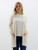 Front view of the Always Faithful Cardigan in a cozy oatmeal shade, styled over a striped top with functional front pockets.