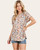 Front-facing floral blouse with fluttery short sleeves and curved hem, styled effortlessly with cutoff denim shorts.