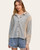 Front-facing view of a woman in a tan and gray striped hooded button-up top layered over a cream tee, paired with blue shorts.