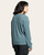 Back view of a woman wearing a spruce heather V-neck knit top with long sleeves, styled with charcoal cargo pants – cozy fall loungewear.