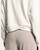 Close-up of the crossover hem detail on the back of a women’s heather oatmeal knit top