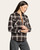 Side view of a woman wearing a buttoned coffee and ivory plaid shirt with front pockets and collared neckline.