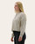Side profile of a woman in a cream ribbed long-sleeve top with floral pattern and button detail neckline.