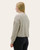 Angled back view of a woman modeling a cream floral knit top with long sleeves and drop shoulders.