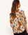 Back view of the Elise Blouse showing the large white floral print pattern on a rust background.