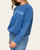 Side view of a woman wearing the blue Mom Club sweatshirt with a relaxed fit.