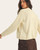 Back view of the cream sweater highlighting the central cable knit detail and ribbed hem.