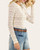 Side profile of the white floral lace long sleeve top tucked into denim.
