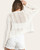 Back view of the lightweight Bailey ivory cotton cardigan worn with white denim shorts.