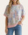 Woman modeling a relaxed-fit short sleeve floral patchwork sweater with pink ribbed trim.