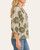 Side profile of a woman wearing a light olive and cream botanical print blouse with 3/4 ruffled sleeves.