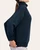 Side profile of a woman modeling the relaxed fit teal navy scuba mock neck sweatshirt with contrasting ribbed cuffs.
