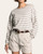 Model wearing the taupe striped Thread and Supply crewneck sweater front-tucked into beige shorts.