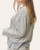 Side view of the Brixton Striped Top highlighting the side slit hem and cuffed long sleeves.