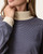Close-up of the Striped Mock Neck Pullover - Navy/Cream, showing fine navy stripes and the ribbed cream mock neck and cuff.