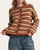Grace Striped Cardigan - Brown/Maroon on a model holding the hem, showing the button front, cream stripes and maroon edging.