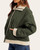Side angle of Luann Quilted Jacket - Olive, showing the quilted sleeve, cream ribbed trim and side pocket.