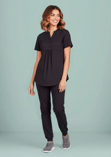 A black women's tunic scrub top is worn with matching pants, featuring a relaxed fit and button detail.