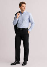 A man in a light blue shirt and black slacks stands confidently, holding a jacket over his shoulder. The slacks feature a logo.