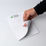 A5 notepad with 25 leaves, featuring a white cover and a logo at the top. A hand is turning a leaf. A5 notepad with 25 leaves, featuring a white cover and a logo at the top. A hand is turning a leaf.